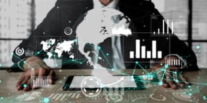A businessman is sitting at a desk with a tablet and a globe on it.