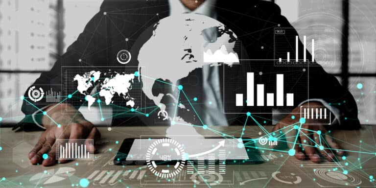 A businessman is sitting at a desk with a tablet and a globe on it.