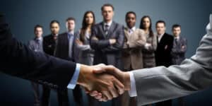 Business people shaking hands in front of a group of people.