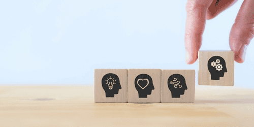 A hand is holding wooden blocks with silhouettes of a person's head.
