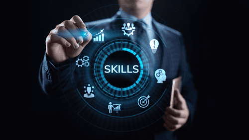 A businessman is pointing to the word skills on a screen.