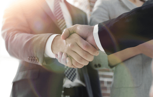 Two business people shaking hands in front of a brick wall.