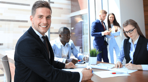 A group of business people sitting at a table in an office.