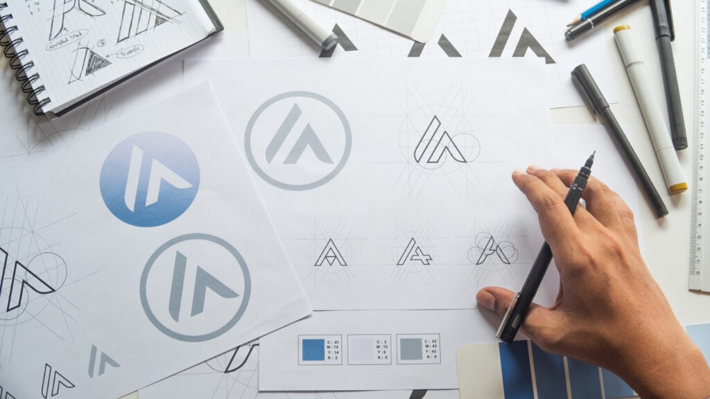 A person is drawing a logo on a piece of paper.
