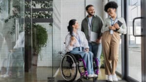 A group of people in a wheelchair standing in front of a glass door.