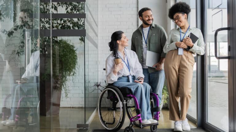 A group of people in a wheelchair standing in front of a glass door.