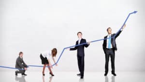 A group of business people standing next to an arrow pointing up.