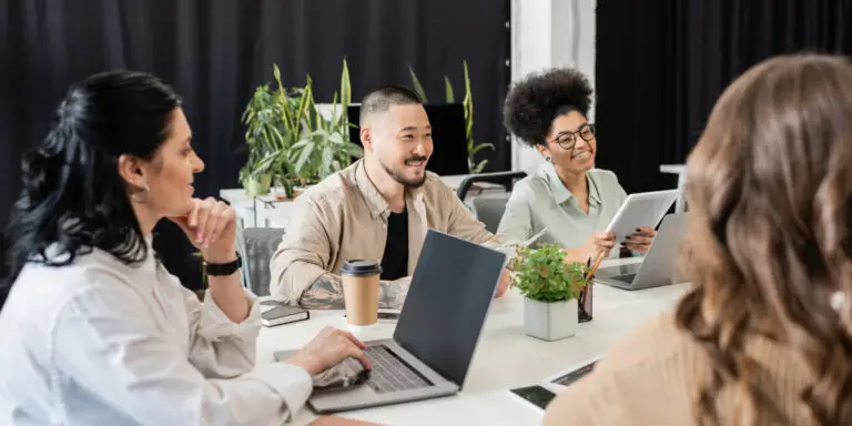 A group of people sitting around a table with laptops.