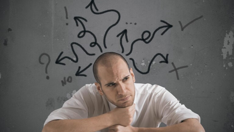 A man sitting in front of a wall with arrows drawn on it.