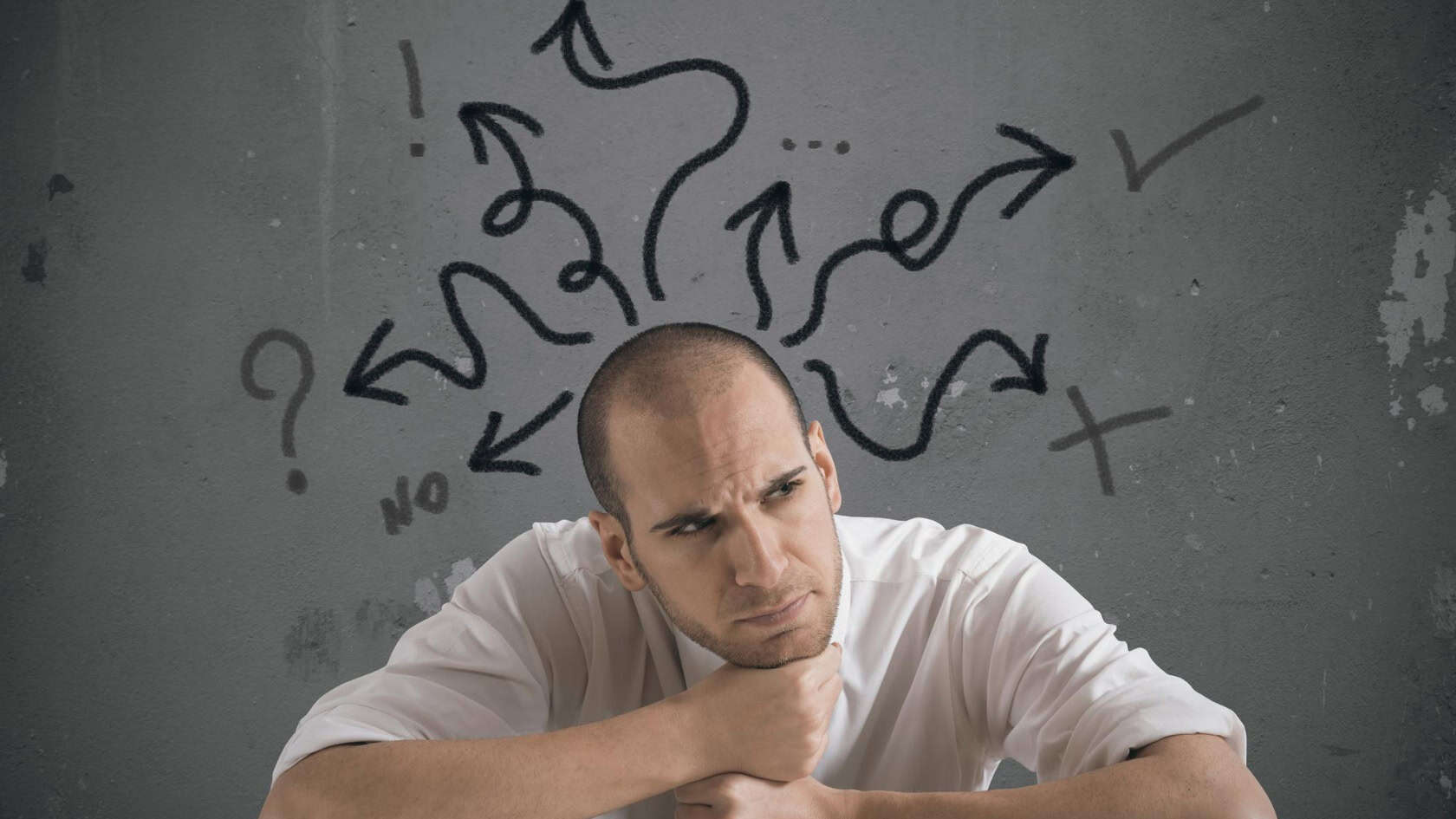 A man sitting in front of a wall with arrows drawn on it.