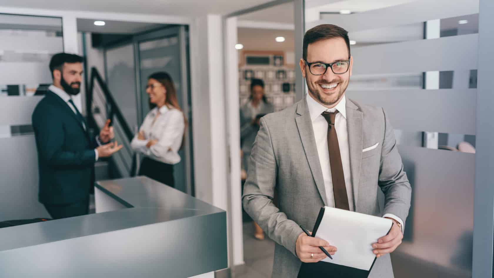 A businessman holding a clipboard in an office.