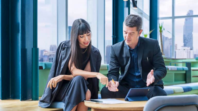 Two business people sitting at a table in an office.