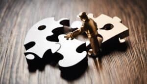 A man holding a puzzle piece on a wooden table.